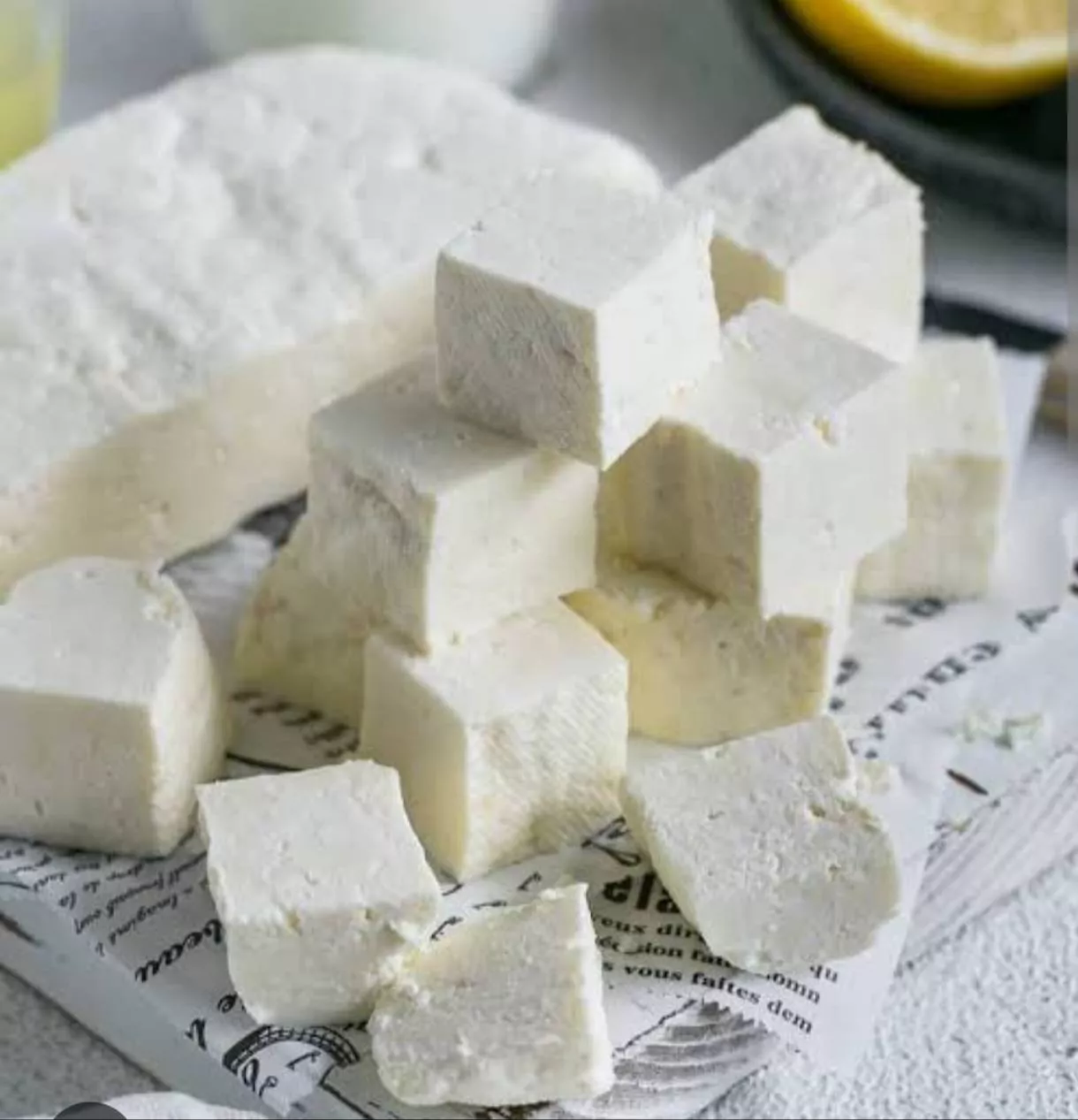 Delicious fresh paneer block on a wooden cutting board, showcasing its creamy texture and freshness, available from VIRK MILK