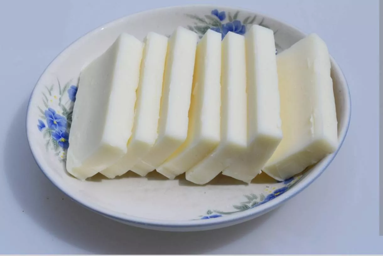 Pure White Butter from VIRK MILK DAIRY in Ismailabad displayed on a wooden board with a knife beside it, showcasing its cream