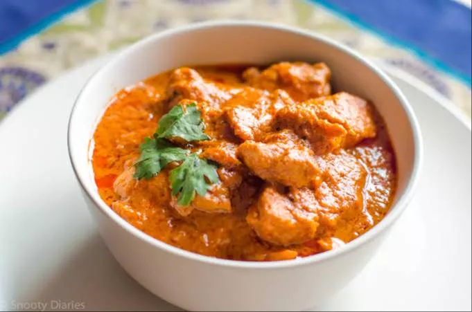 Rich and creamy Butter Chicken Curry served with naan in TIBRI — a flavorful dish featuring tender chicken in a spiced sauce.