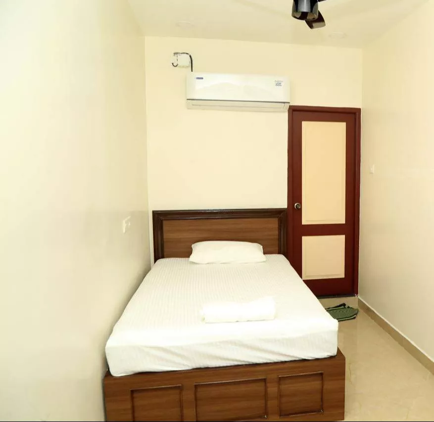 Cozy AC single bed room designed for one guest at SUDHA GRAND in Chennai, featuring a comfortable bed and essential amenities