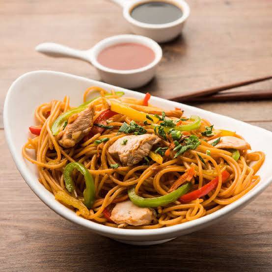 Plate of Asian Cuisine Chicken Stir-Fry Noodles in Kolkata with colorful vegetables and chicken